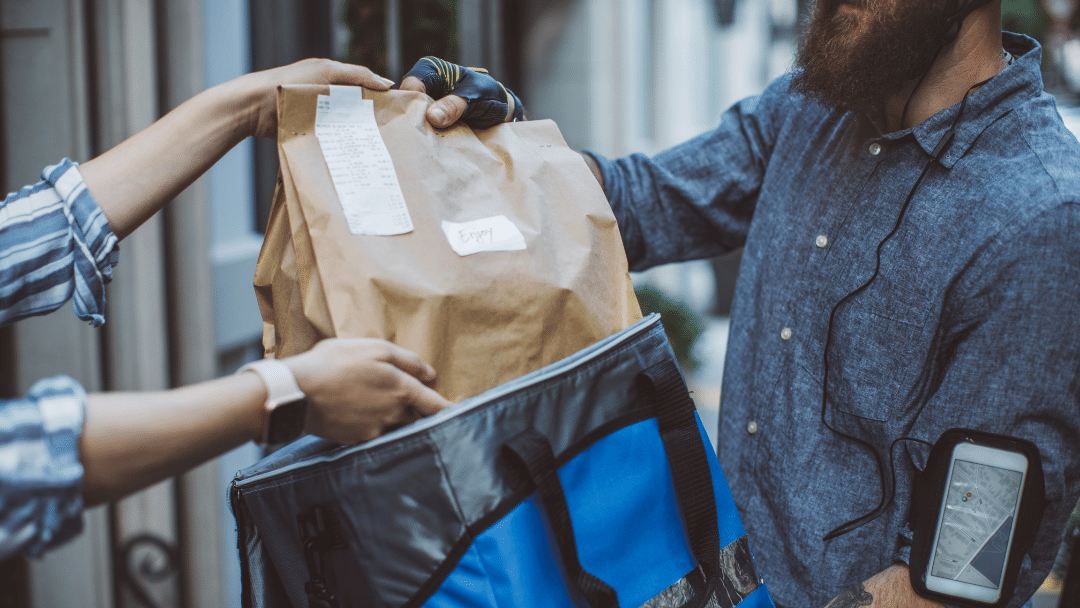 Imagen de un repartidor de delivery entregando al cliente su pedido